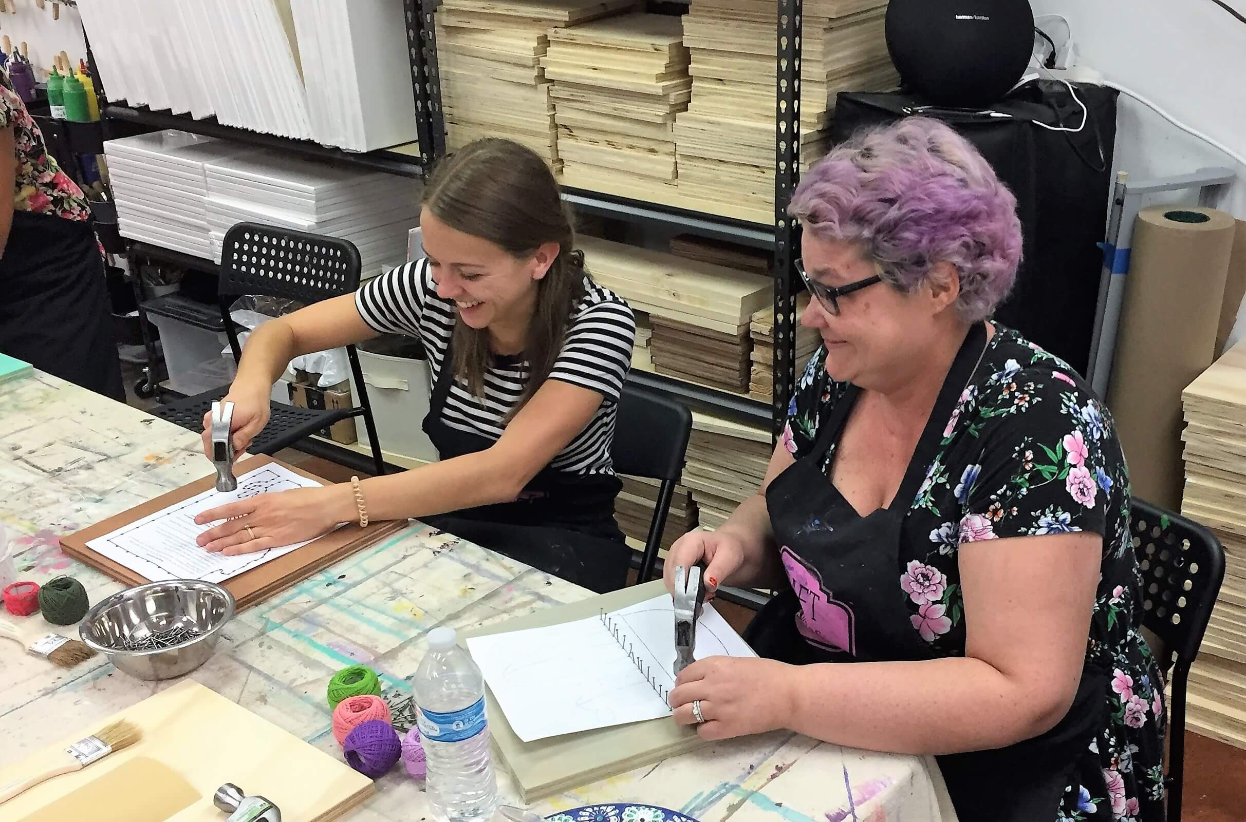 Two friends smiling while making string art at Craft Nights